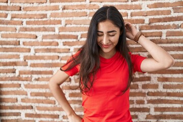 Young teenager girl standing over bricks wall stretching back, tired and relaxed, sleepy and yawning for early morning