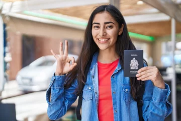 Photo sur Plexiglas Canada Young teenager girl holding canada passport doing ok sign with fingers, smiling friendly gesturing excellent symbol