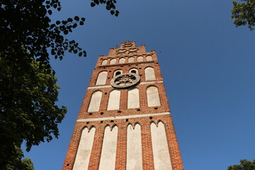 Wieża z czerwonej cegły z dużym zegarem na tle niebieskiego nieba - obrazy, fototapety, plakaty