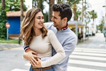 Obraz premium Young hispanic couple hugging in love at the city. Girlfriend and boyfriend together in love walking on the street
