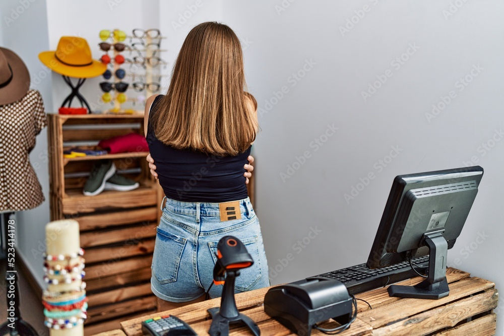 Poster young brunette woman holding banner with open text at retail shop hugging oneself happy and positive