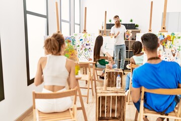 Group of people smiling happy drawing in paint class at art studio.