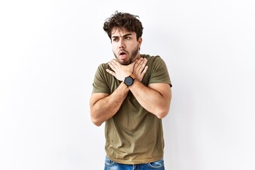 Hispanic man standing over isolated white background shouting suffocate because painful strangle....