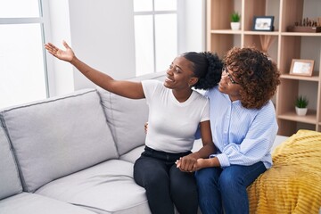 Obraz premium African american women mother and daughter sitting together on sofa at home