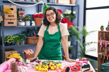 Young woman florist smiling confident leaning on table at florist