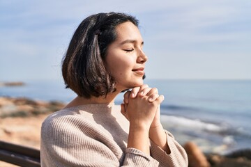 Young woman smiling confident praying at seaside