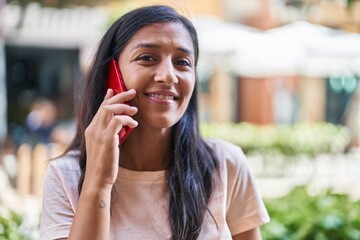 Young beautiful hispanic woman smiling confident talking on the smartphone at street