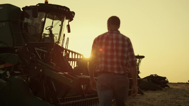 Farmer checking combine working on rye golden countryside field producing wheat
