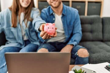 Couple holding piggy bank at home.