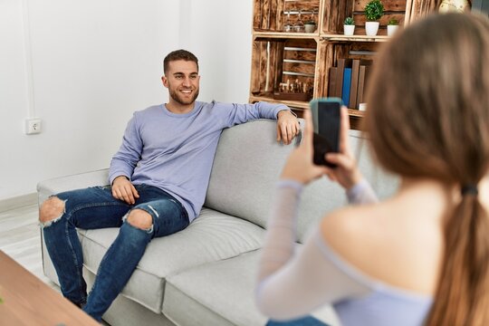 Young woman making picture of her boyfriend using smartphone at home.