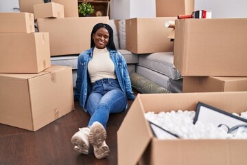African american woman smiling confident sitting on floor at new home