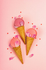 Ice cream waffle cones with macarons on pink background. Sweet dessert, summer concept