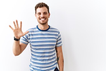 Fototapeta premium Handsome young man standing over isolated background showing and pointing up with fingers number five while smiling confident and happy.