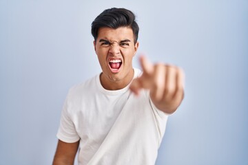 Fototapeta premium Hispanic man standing over blue background pointing displeased and frustrated to the camera, angry and furious with you