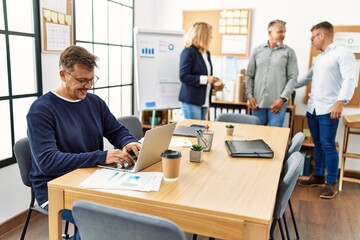 Middle age business worker smiling happy working while partners have break time at the office.