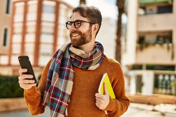 young caucasian man with beard  using smartphone outdoors on a sunny day