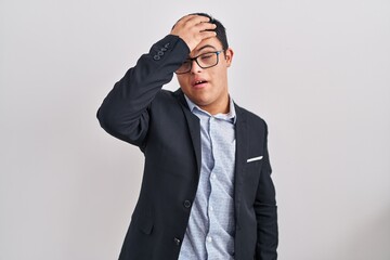 Young hispanic man with down syndrome wearing business style surprised with hand on head for...