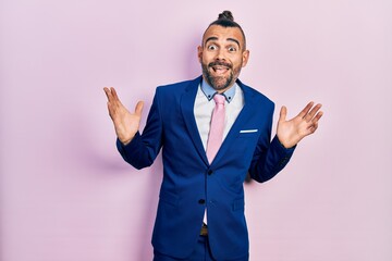 Young hispanic man wearing business suit and tie celebrating crazy and amazed for success with arms raised and open eyes screaming excited. winner concept