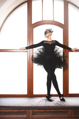 graceful ballerina in black swan dress against wgite background. Young ballet dancer practicing...