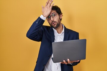 Handsome latin man working using computer laptop surprised with hand on head for mistake, remember error. forgot, bad memory concept.