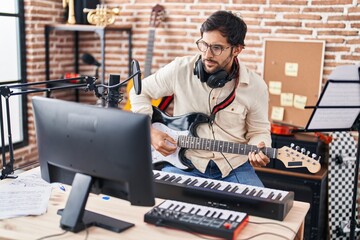 Young hispanic man musician playing electrical guitar at music studio