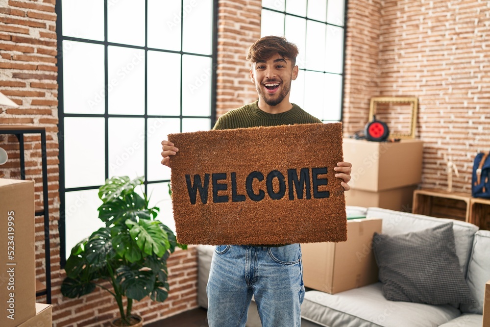 Sticker Arab man with beard holding welcome doormat smiling and laughing hard out loud because funny crazy joke.