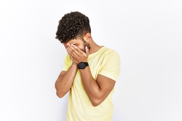 Arab young man standing over isolated background with sad expression covering face with hands while crying. depression concept.