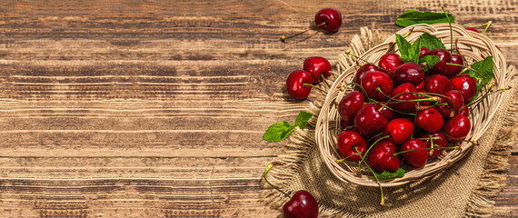 Ripe sweet cherries with fresh mint leaves, traditional summer fruits. Trendy light, vintage napkin