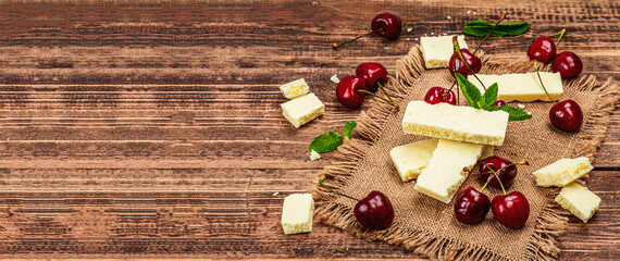 Fototapeta na wymiar Ripe sweet cherries with fresh mint leaves and white chocolate, traditional summer fruits