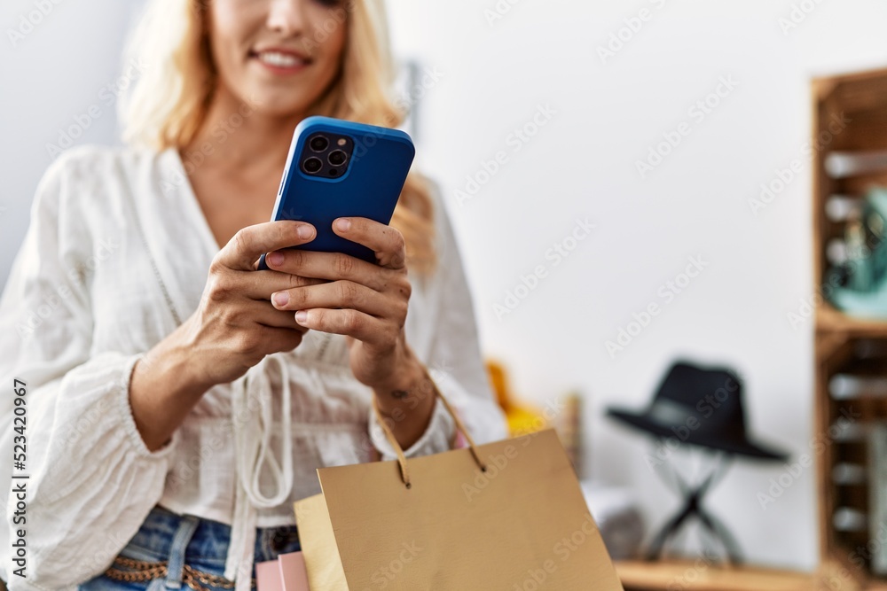 Canvas Prints Young blonde woman using smartphone shopping at clothing store