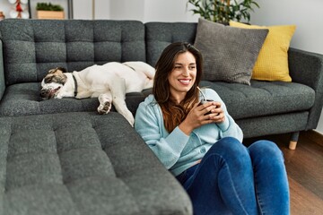 Young woman drinking mate infusion sitting with dog at home