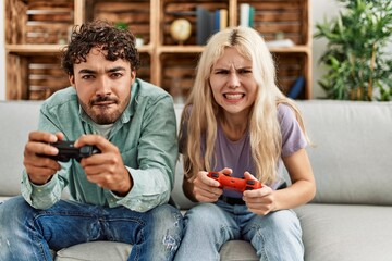 Young couple screaming and playing video game at home.