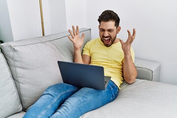 Young hispanic man having video call lying on the sofa at home.