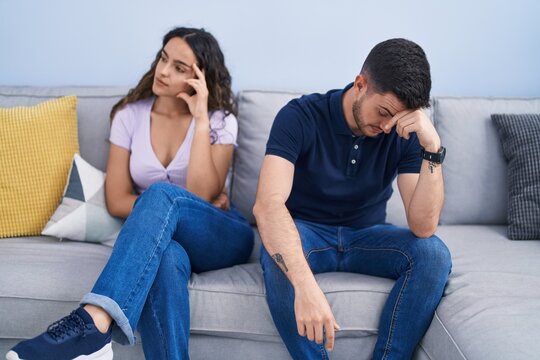 Young hispanic couple arguing sitting on sofa at home