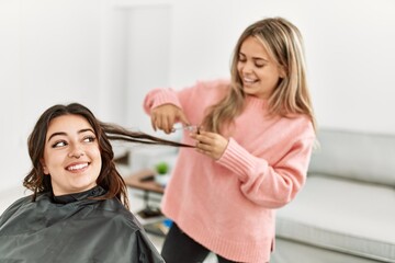 Young woman cutting hair to her girlfriend at home.