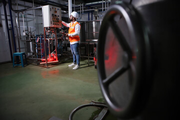 Naklejka na ściany i meble Factory worker inspecting production line of drink production in factory , Concept of food industry
