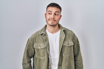 Young hispanic man standing over isolated background smiling looking to the side and staring away thinking.