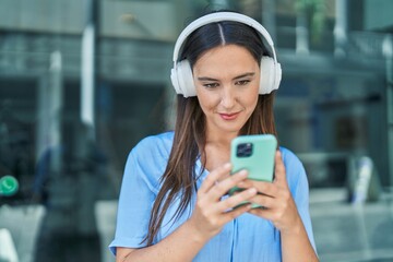 Young beautiful hispanic woman smiling confident listening to music at street