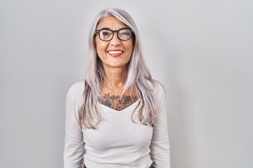 Middle age woman with grey hair standing over white background with a happy and cool smile on face. lucky person.