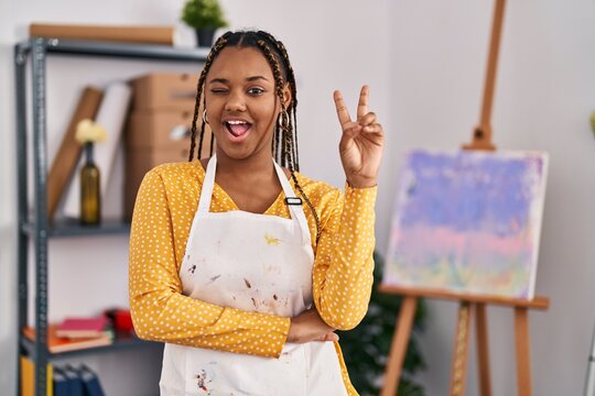 African american woman with braids at art studio smiling with happy face winking at the camera doing victory sign. number two.