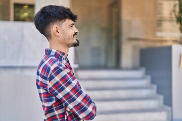 Young hispanic man smiling confident standing with arms crossed gesture at street