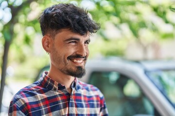 Young hispanic man smiling confident looking to the side at street