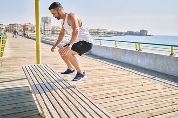 Hispanic man working out jumping a bench outdoors on a sunny day