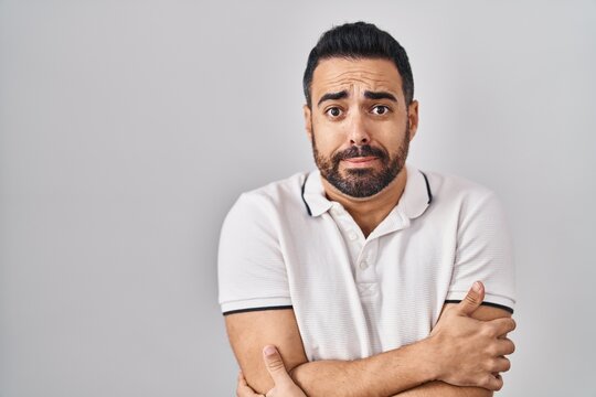 Young Hispanic Man With Beard Wearing Casual Clothes Over White Background Shaking And Freezing For Winter Cold With Sad And Shock Expression On Face