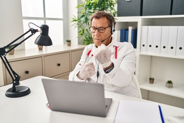 Senior doctor man working on online appointment ready to fight with fist defense gesture, angry and...
