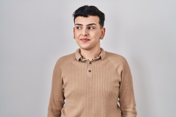 Non binary person standing over isolated background smiling looking to the side and staring away thinking.