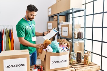 Young arab man wearing volunteer uniform working at charity center