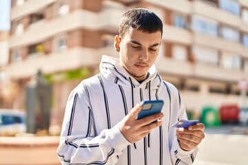 Young man using smartphone and credit card at street