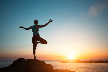 Silhouette woman yoga, meditation on the ocean beach seeing off the sun.
