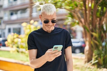 Fototapeta premium Young caucasian man smiling confident using smartphone at park